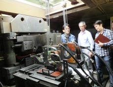 電磁濃縮超強磁場発生装置の解説をする松田准教授（左）
