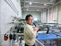 強磁場発生装置用大型コンデンサーの前で説明する松田准教授