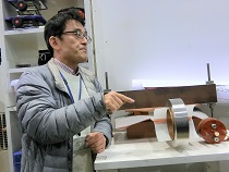 電磁濃縮法のコイルについて説明をする松田准教授