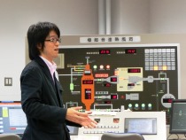 極超音速熱風洞のパネルの前で説明する鈴木教授