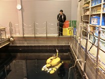 自律型海中ロボット「Tri-TON 2」の解説をする巻准教授